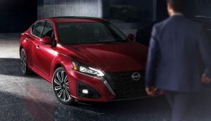 A person in a suit walking up to a read 2023 Nissan Altima