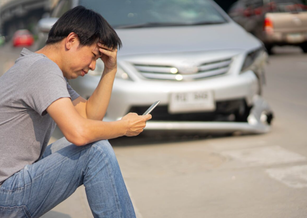 A person sitting near their car after a minor collision.