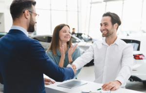 Two people at a car dealership making a sale with an agent near Fishers, Indiana.