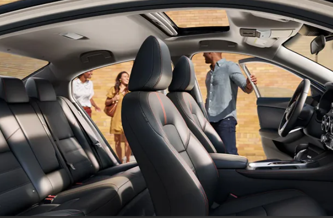 The interior of a Nissan Sentra, with three people opening the doors and talking to each other. Photo taken near Fishers, IN