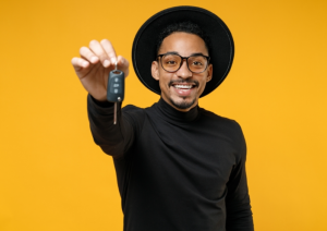A person holding up the keys to their new car in front of a yellow backround near Fishers, Indiana