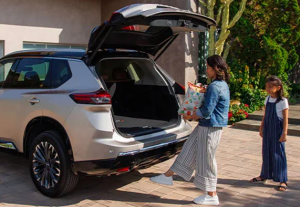 A person opening the rear liftgate of their 2025 Nissan Rogue to place bags of goods inside near Fishers, Indiana
