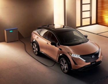 Nissan ARIYA plugged-in and charging outside a home | Ed Martin Nissan of Fishers in Fishers IN