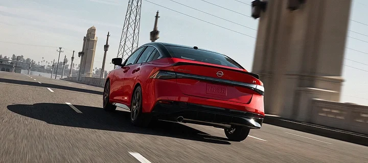 Red 2026 Nissan Sentra SR driving across a city bridge