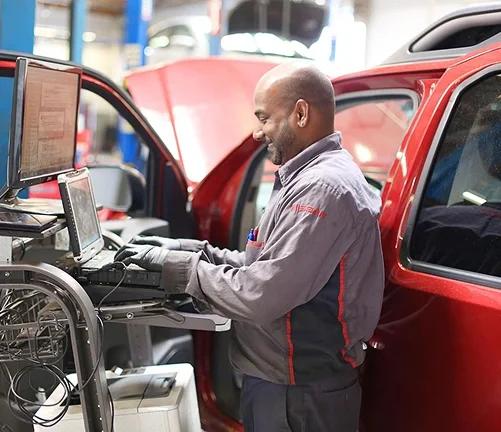 Nissan technician running vehicle diagnostics in the service bay